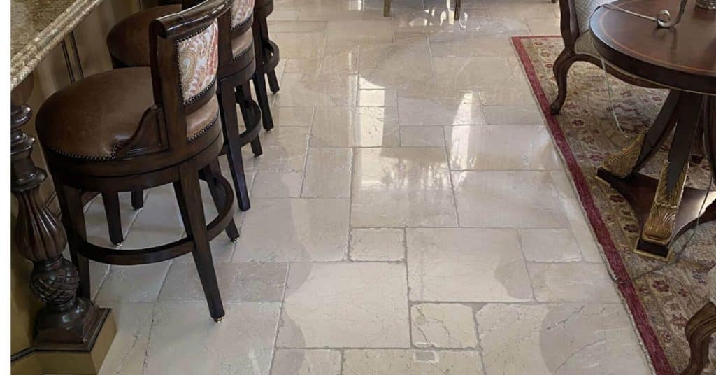 Refinished beige marble floor in a kitchen bar area showing renewed shine and restored surface detail.